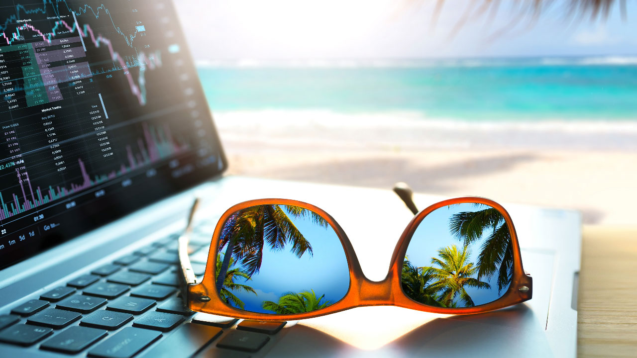A laptop and sunglasses rest in front of a beach view